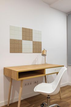 Stylish and minimalist room interior with modern comfortable workplace. Wooden table and floor with white wall and chair