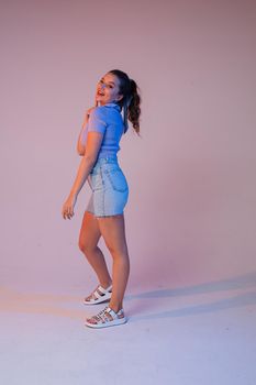 a woman in denim shorts, sunglasses in the studio on an interesting beautiful background.