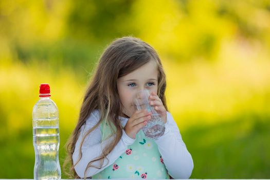 girl drinking water on the background of nature