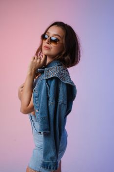 a woman in denim shorts, sunglasses in the studio on an interesting beautiful background.