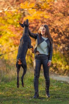 girl plays with a Doberman dog with a ball