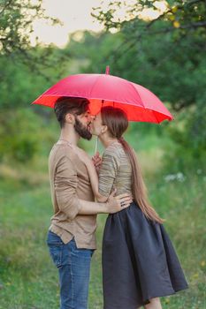 couple outdoors under a red umbrella