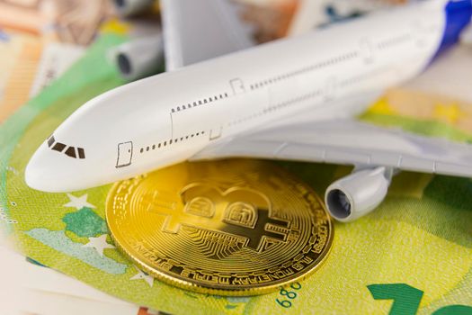 airplane and bitcoin stand on euro banknotes close-up