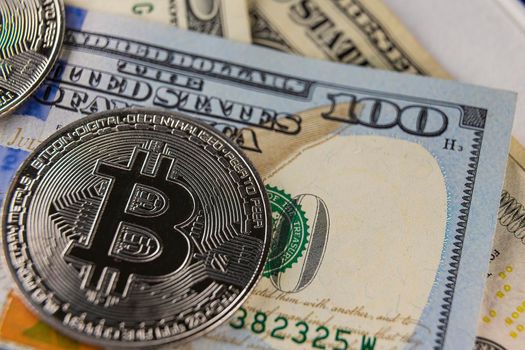 bitcoin coin flying on hundred dollar bill close up