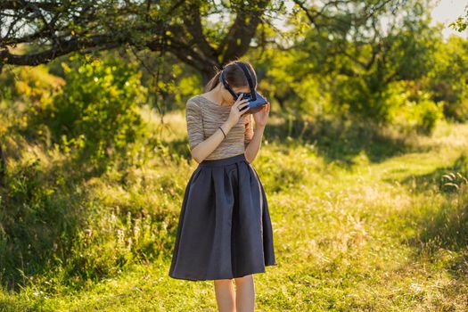 girl in virtual reality glasses on the background of green trees