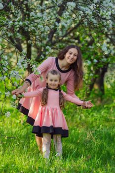 mother and daughter are walking through the blooming garden