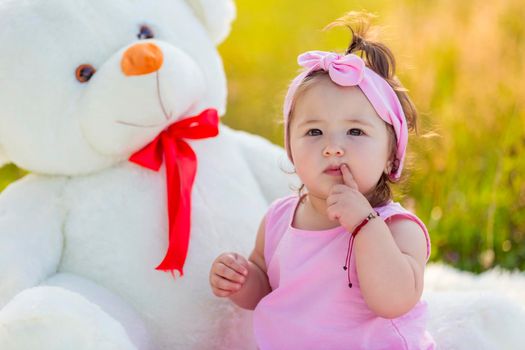 little girl with a big teddy bear in nature