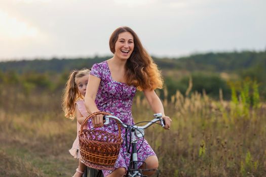 mother rides her daughter on a bike across the lawn