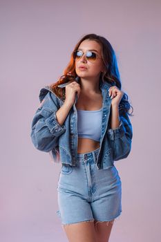 a woman in denim shorts, sunglasses in the studio on an interesting beautiful background.