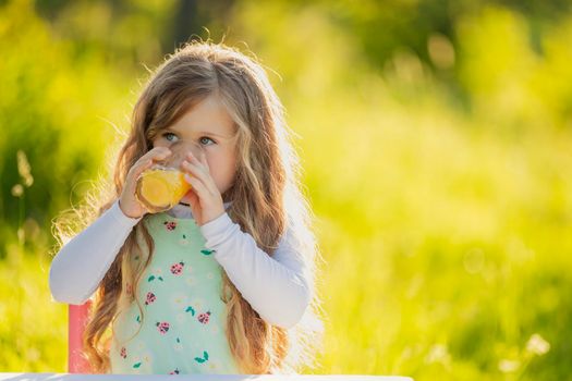child drinking orange juice while outdoors