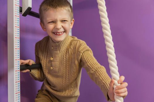 boy on the wall bars holding on to the rope