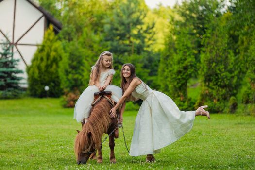mother with daughter and pony walking in the yard