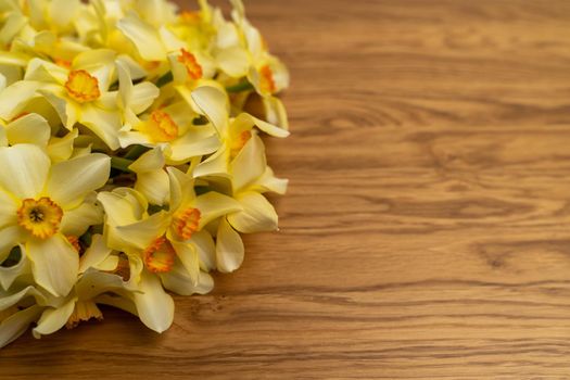 On the left is a large bouquet of yellow daffodils on an wooden background. Copy space. Can be used as a card, background for screensavers, greetings