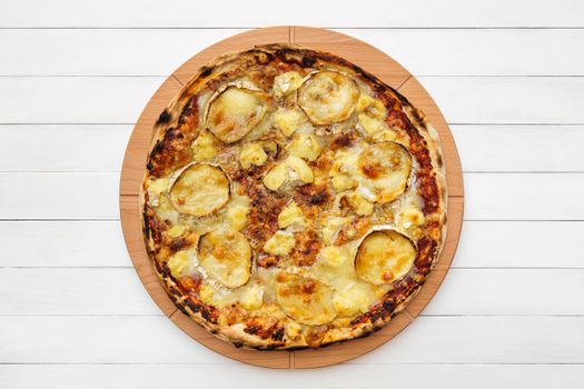 Whole round pizza topped with goat cheese on wooden plate. Top view on white board background. Copy space.