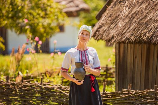 woman in Ukrainian national costume with a jug in her hands on the street