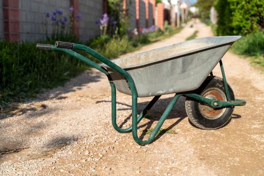 An old garden car stands on the road of a holiday village. The concept of work in the country, gardening.