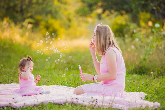 mother and daughter blow bubbles in the summer garden