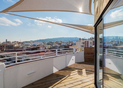 Sunny empty terrace with a sunshade. View to the hill and the city. Barcelona, Spain