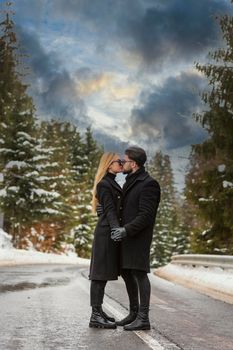 couple kissing against the backdrop of a snow-covered mountain forest and a highway