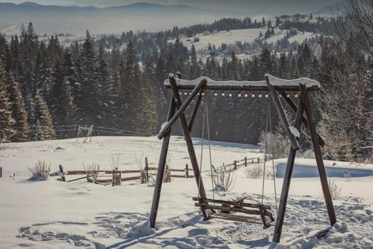 wooden swing against the backdrop of forest snow-capped mountains