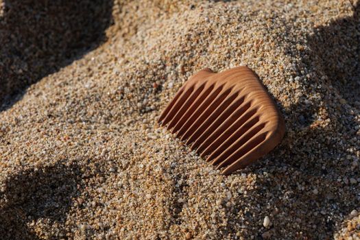 Handmade wooden comb on sand at the beach. Used for head massage and combing. Hair care concept