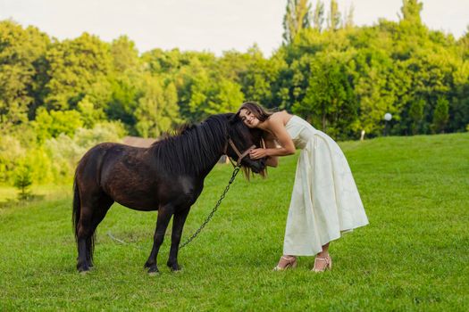 woman petting a pony standing on the lawn