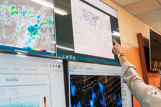 Weather prediction by an unrecognizable scientist pointing at the graphs on a screen.