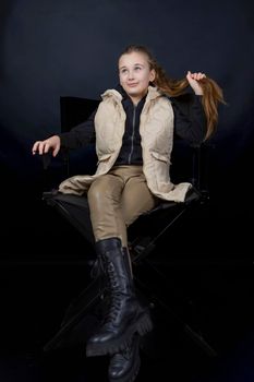 girl sitting on a chair holding her hair on a black background