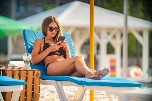 girl in sunglasses lies on a sun lounger on the beach