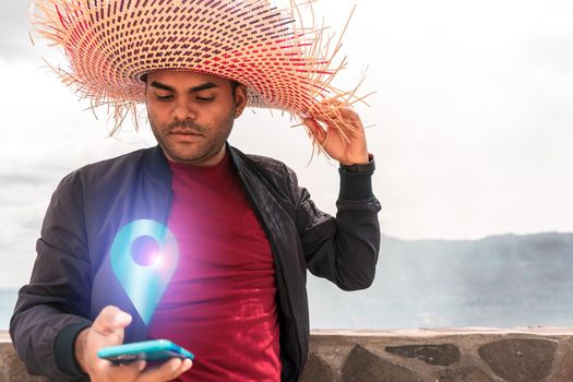 Latin man with striking hat searching for a gps location on his cell phone during an adventure trip in a volcano