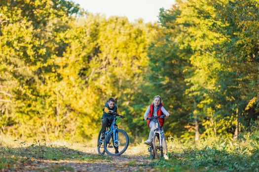 happy kids ride a bike in the autumn forest