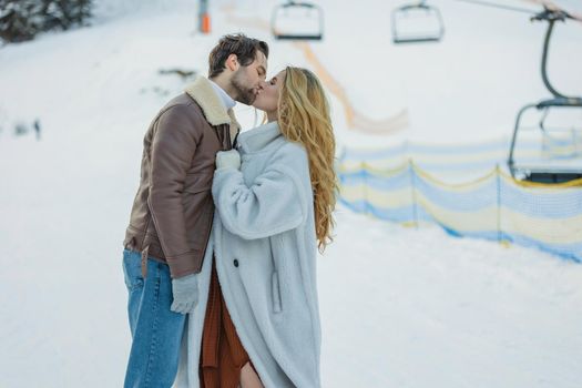beautiful couple hugging in winter on the background of a snowy mountain