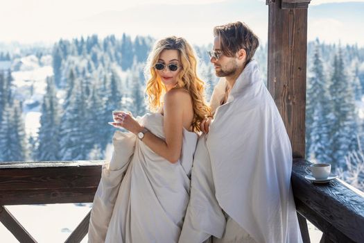 couple in winter in blankets on the background of mountains