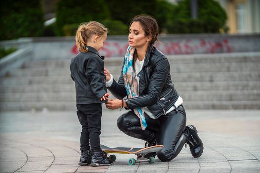 mom with daughter and skate on the background of the city