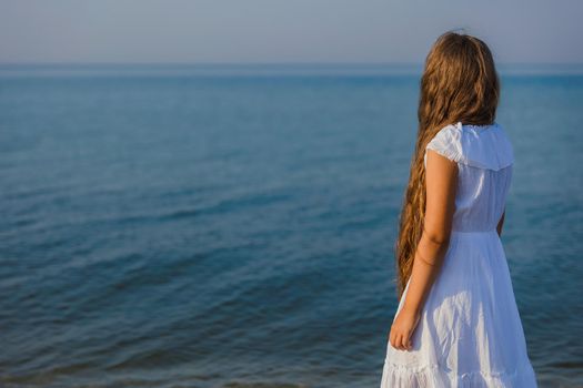 girl in white dress walking on the beach