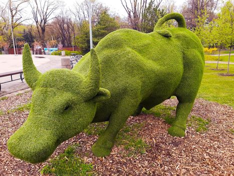 Decorative sculpture of a bull in a city park close-up.