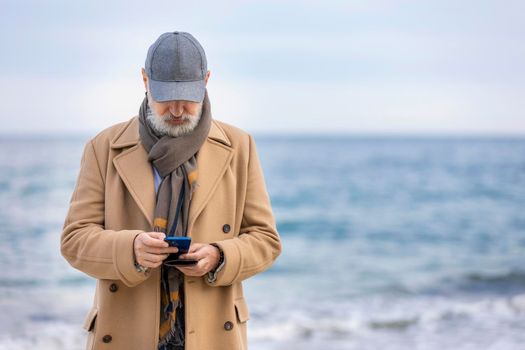 an aged man walking along the beach against the background of the sea