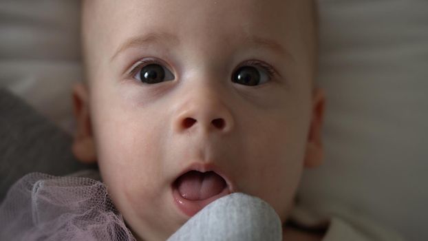 Close-up Happy playful kid 6 month old. Newborn boy looking at camera after bath shower on white soft bed. baby child waking time before bedtime with Toy. Childhood, motherhood, family, infant concept.