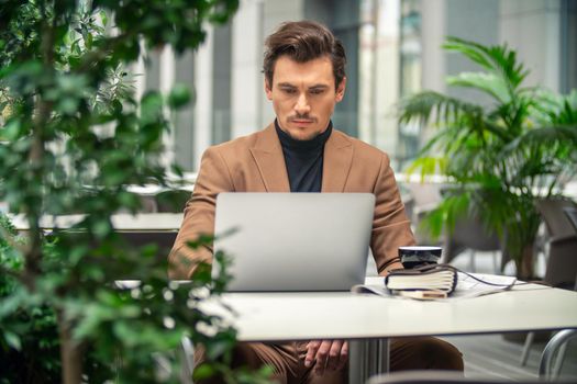 businessman sitting at a table in a cafe with a laptop