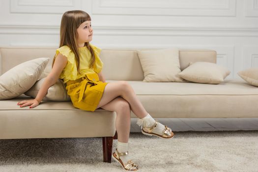 a girl in a yellow suit sits on sofas