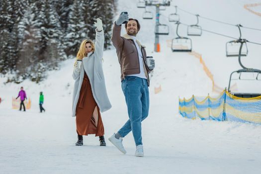 young couple taking a selfie on the background of a snowy mountain