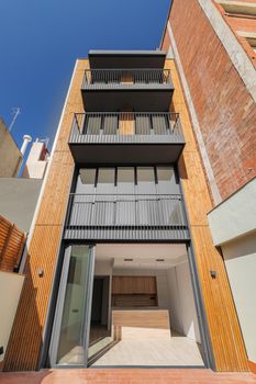 Frontal view of wooden and metal contemporary building facade with vertical stripes of timbers . Outdoor exterior of narrow modern house in Barcelona, Spain.