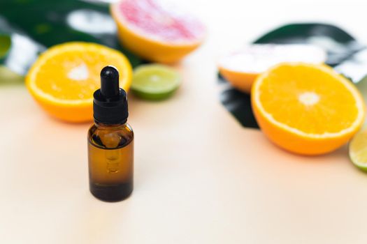 Serum or essential citrus oil with vitamin C from lime, orange and lemon, beauty care, anti-aging natural cosmetics on the background of citrus fruits
