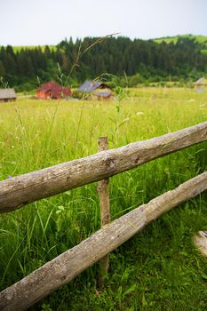 Wooden fence against the summer landscape in the Ukrainian Carpathian Mountains.