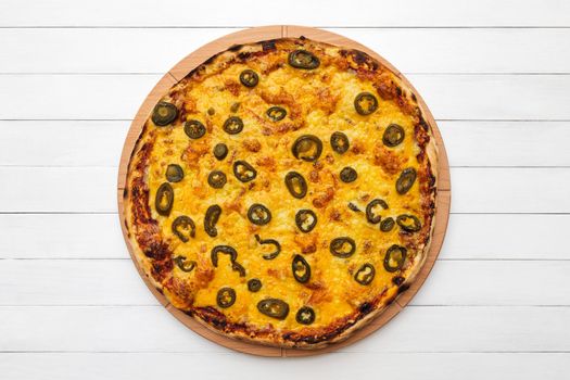 Whole round pizza topped with olives and cheese on wooden plate. Top view on white board background. Copy space.
