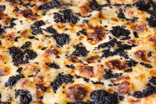 Close-up of pizza topped with with truffles and cheese. Macro shot of delicious products. Selective focus.