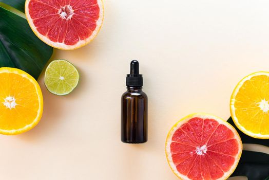 Vitamin C serum in an amber bottle with a pipette on a background of orange citrus fruits with green leaves. Citrus essential oil, aromatherapy cosmetics. Organic SPA cosmetics with herbal ingredients. Flat lay.