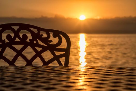 A silhouette of a chair and table at sunrise on the sea beach