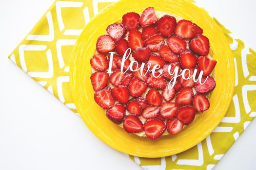 Bright and delicious strawberry cake on a yellow napkin, the inscription I love you.