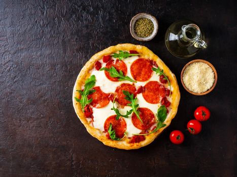 hot homemade Italian pepperoni pizza with salami, mozzarella on a dark brown stone table, top view, copy space.